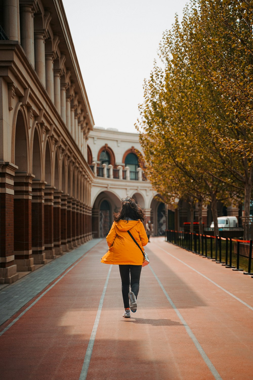 Frau im roten Kittel geht tagsüber auf dem Bürgersteig spazieren