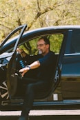 man in black crew neck t-shirt and black pants sitting on blue car