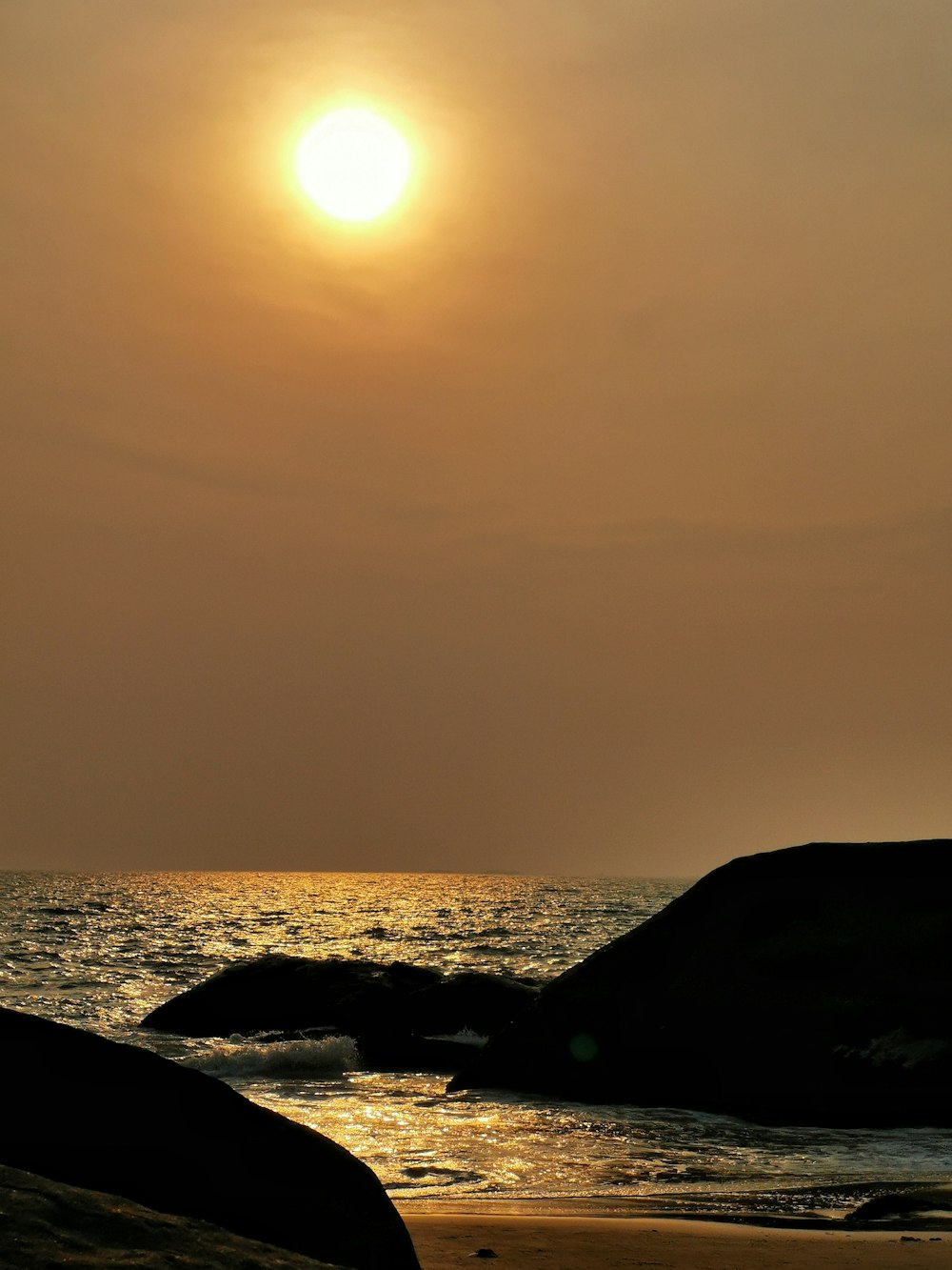 silhouette of mountain near body of water during sunset