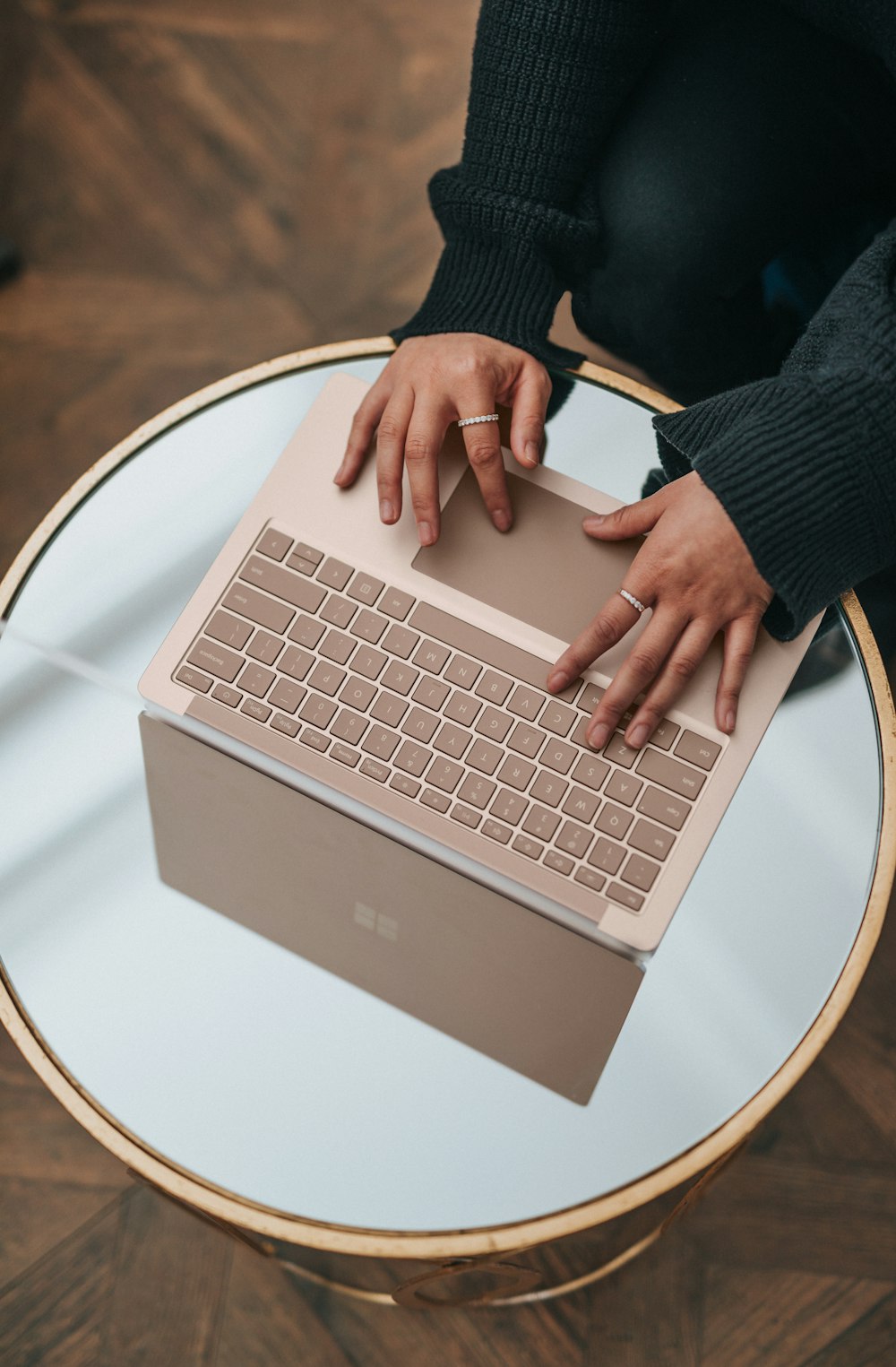 person using Microsoft Surface Laptop on white round table