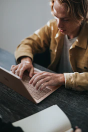 man in yellow dress shirt using Microsoft Surface Laptop