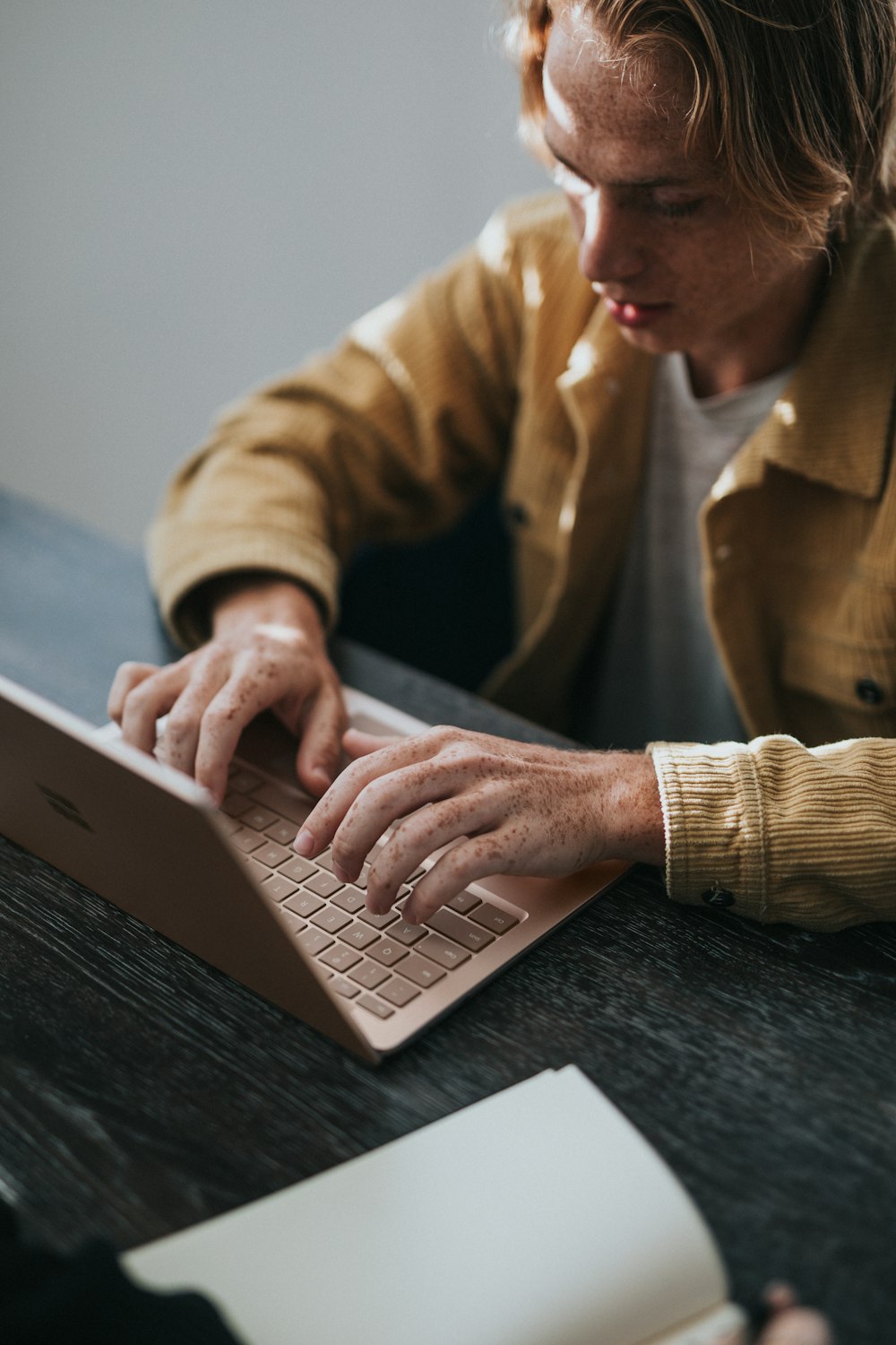 Microsoft Surface ラップトップを使用する黄色のドレスシャツを着た男性