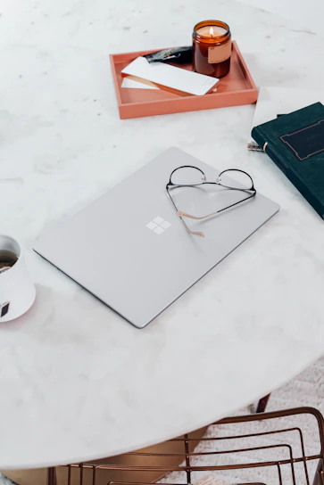 A sleek, minimalist workspace with a laptop, notebook, and a cup of coffee bathed in warm golden orange light.