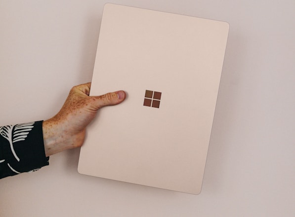 person holding sandstone microsoft Surface laptop laptop