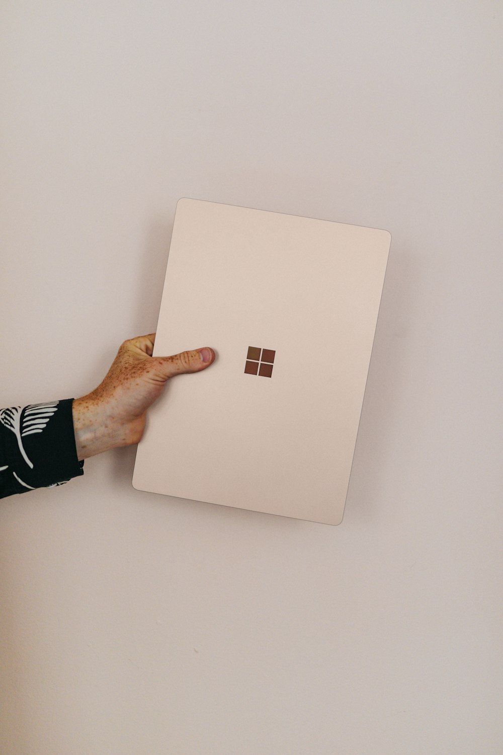 person holding sandstone microsoft Surface laptop laptop