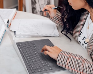 woman in white and black plaid long sleeve shirt using black and silver laptop computer