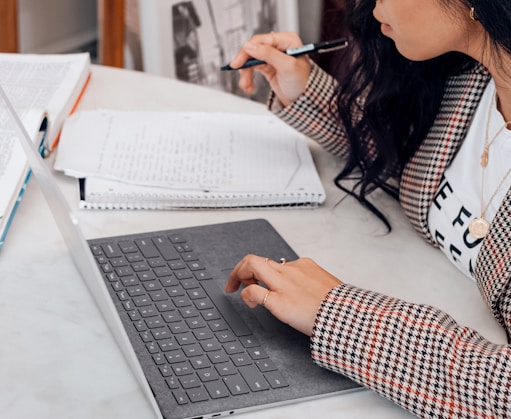 woman in white and black plaid long sleeve shirt using black and silver laptop computer