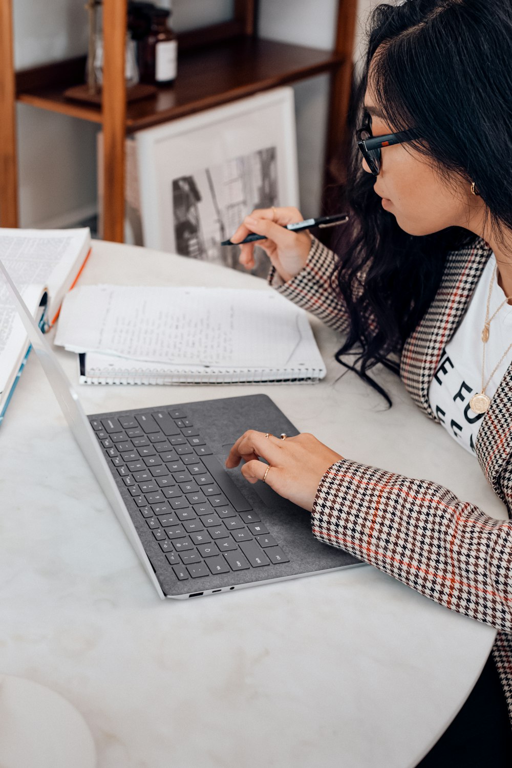 woman in white and black plaid long sleeve shirt using black and silver laptop computer