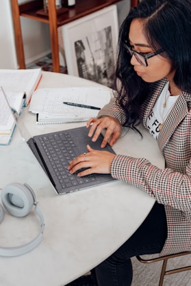 woman in red and white plaid long sleeve shirt using platinum coloured microsoft surface laptop computer