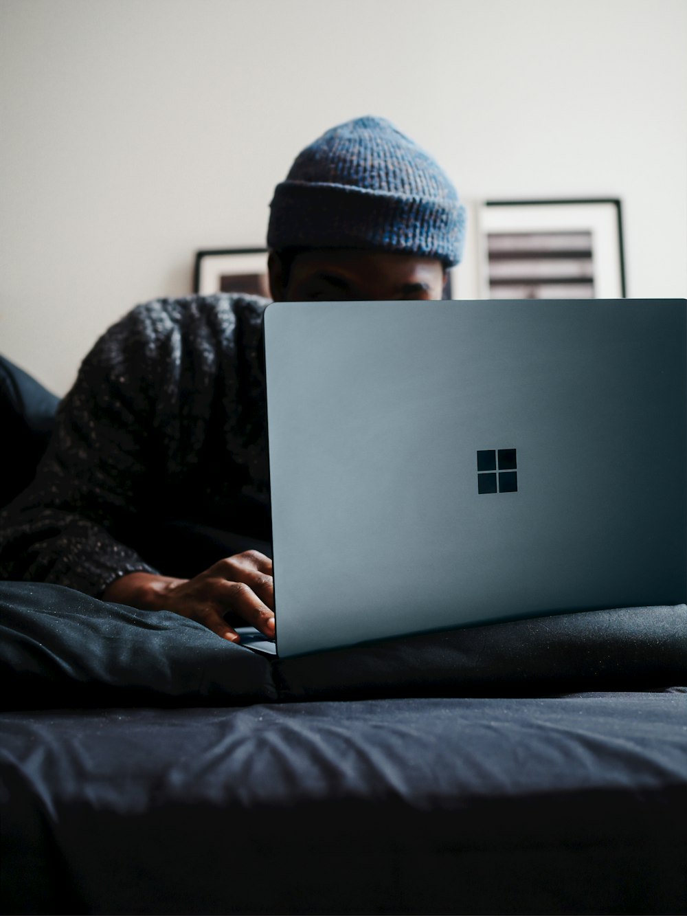 코발트 블루 색상의 Microsoft Surface 컴퓨터를 사용하는 회색 니트 캡을 쓴 사람 