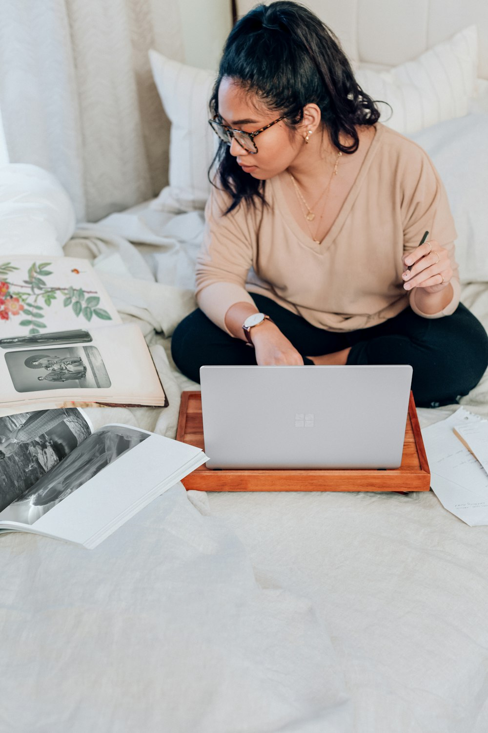 ベージュの長袖シャツを着た女性、プラチナの Microsoft Surface を使用