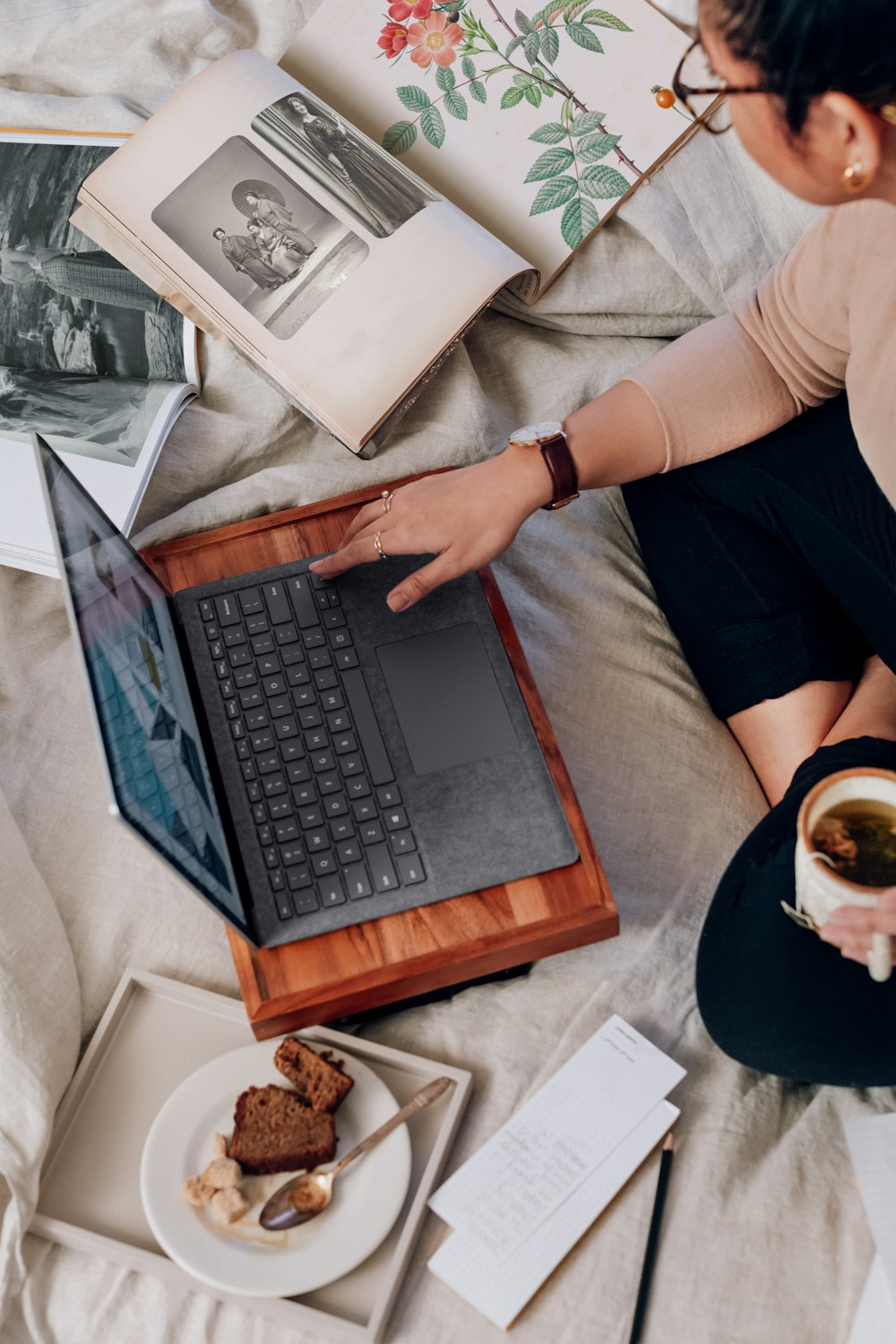 person in beige shirt using platinum Microsoft surface laptop computer