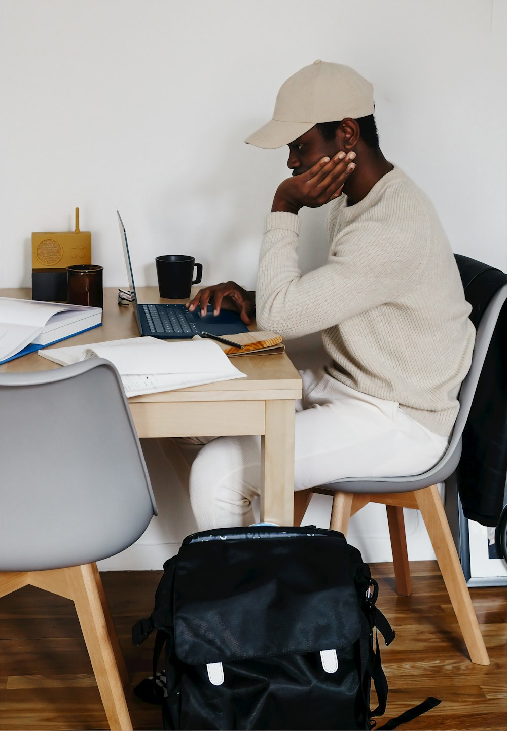 Mann im weißen Pullover sitzt auf dem Stuhl mit Microsoft Surface Laptop 3  