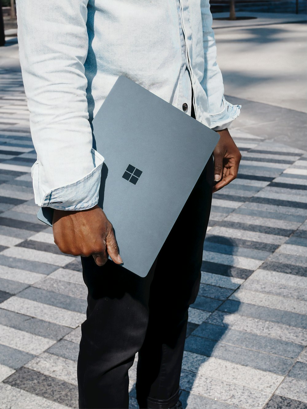 man in dress shirt holding blue microsoft surface laptop computer