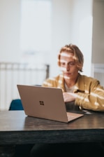 man in yellow jacket using microsoft surface laptop 