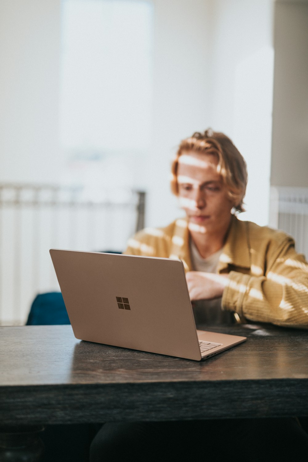 man in yellow jacket using microsoft surface laptop 