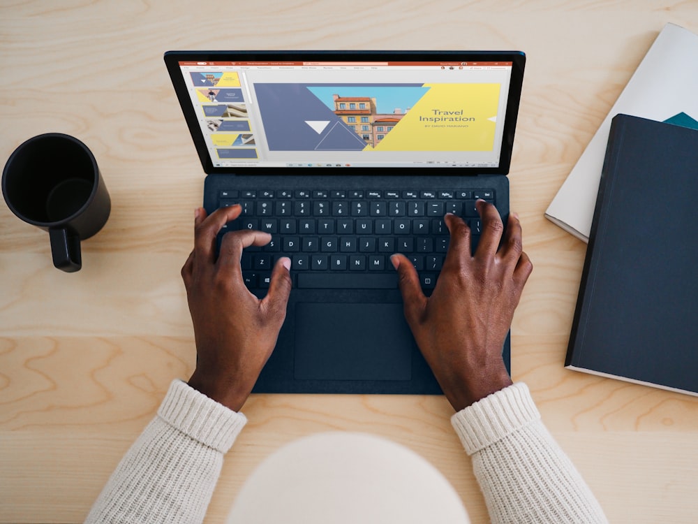 person using cobalt blue microsoft surface laptop computer on a table 