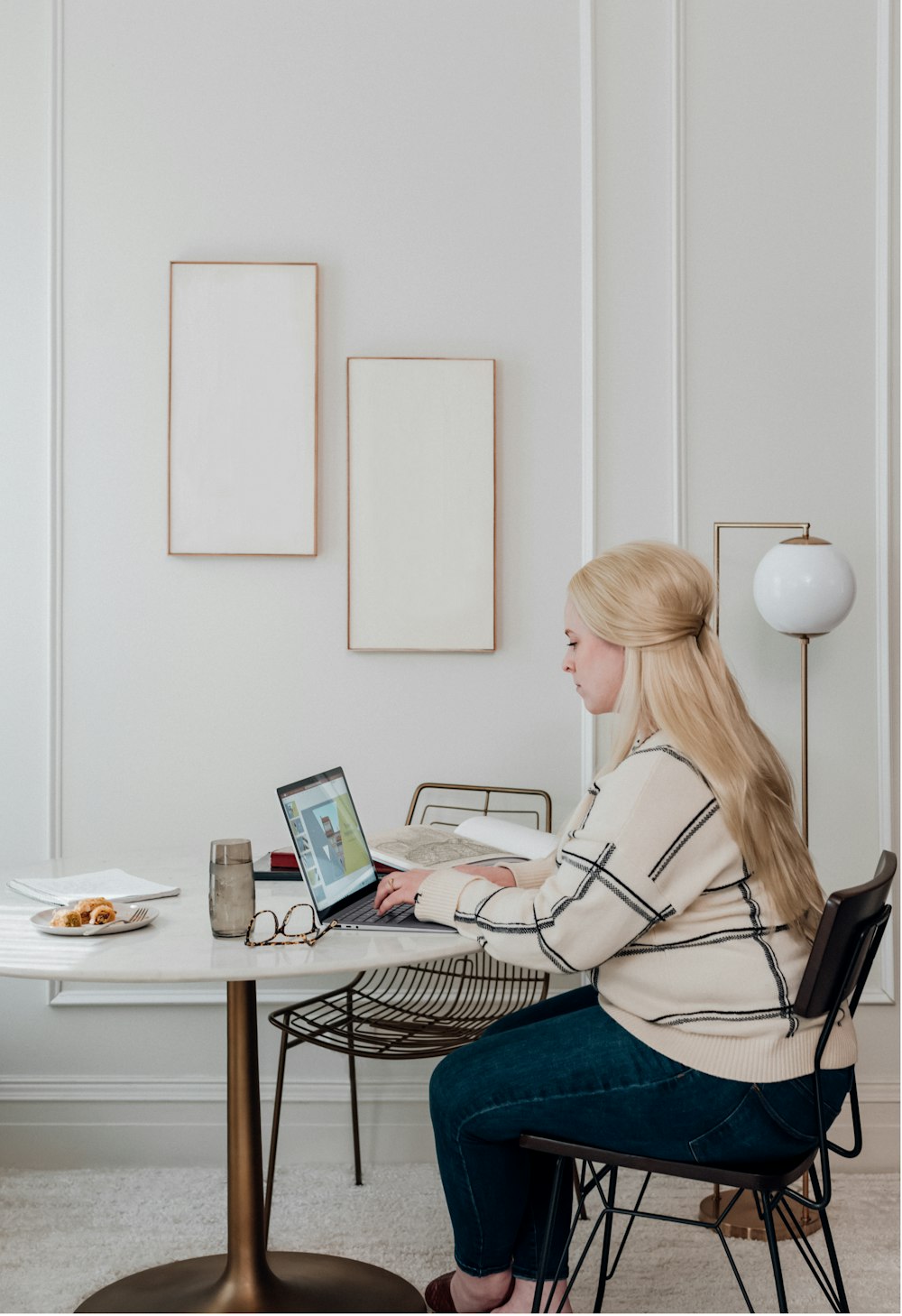 woman in white long sleeve shirt sitting on chair in front of microsoft surface laptop computer