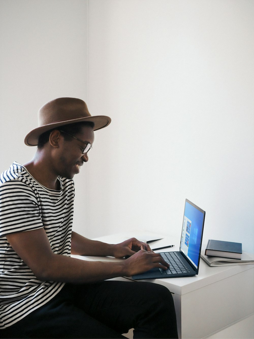 白と黒の縞模様のシャツを着た男、Microsoft Surface コバルト ブルーのラップトップ コンピューターを使用