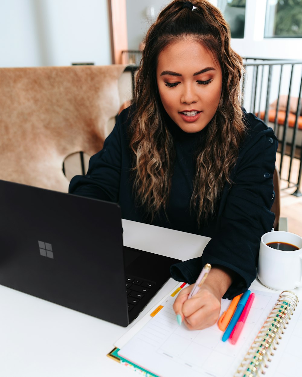 woman in black sweater with a black microsoft surface laptop on a table 
