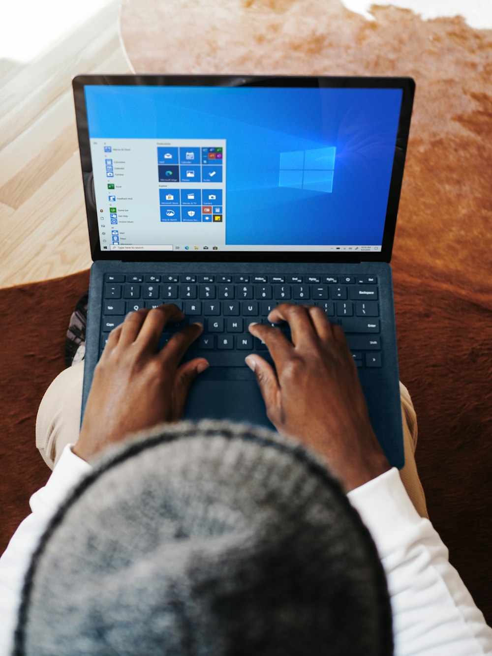 person using cobalt blue microsoft surface laptop computer