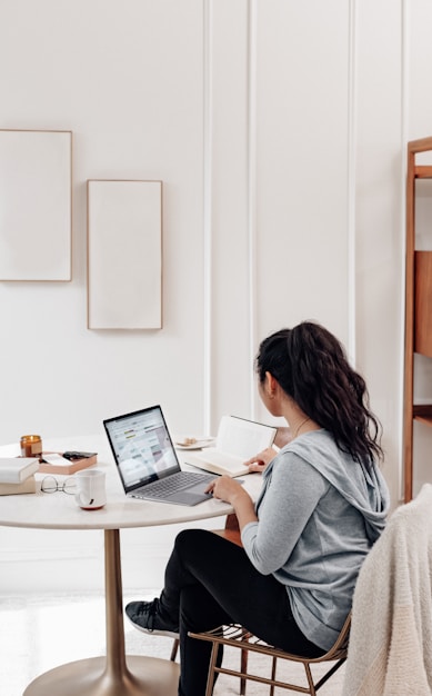 woman in gray sweater using microsoft surface laptop 