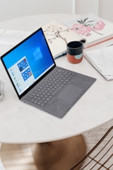 gray microsoft surface laptop computer on white table