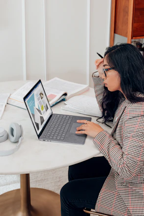 A student analyzing data charts on a laptop in a cozy study room.