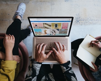 person using microsoft surface laptop on lap with two other people