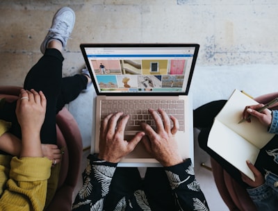 person using microsoft surface laptop on lap with two other people