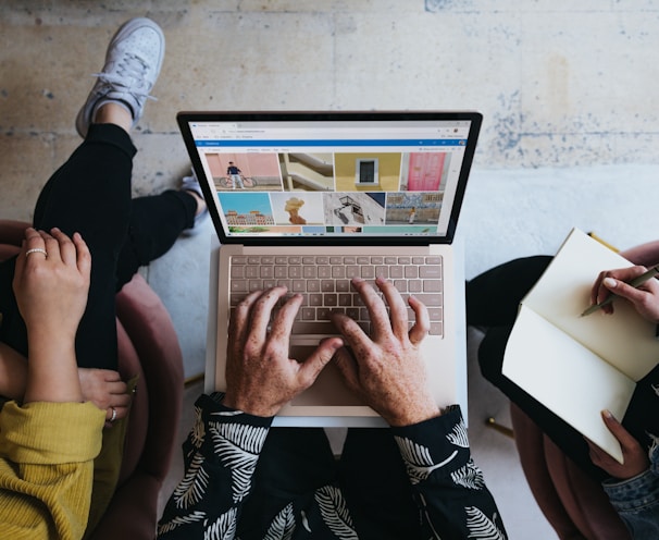 person using microsoft surface laptop on lap with two other people