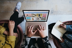 person using microsoft surface laptop on lap with two other people