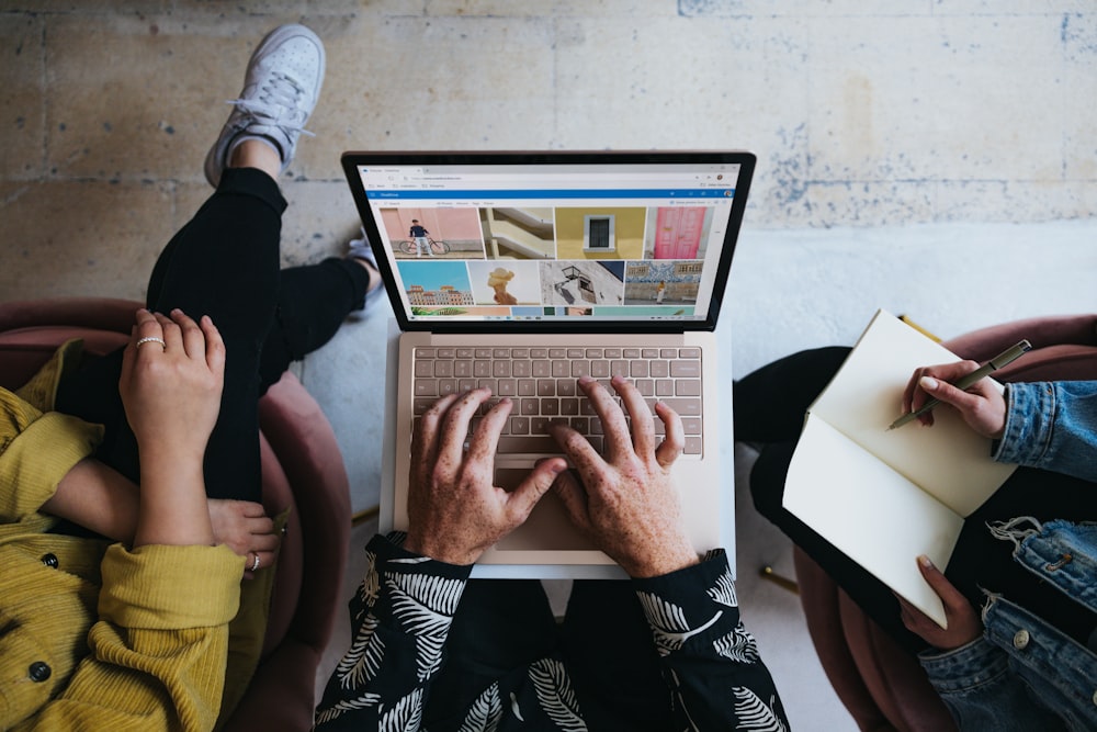 Persona usando Microsoft Surface Laptop en el regazo con otras dos personas