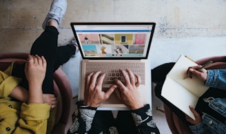 person using microsoft surface laptop on lap with two other people