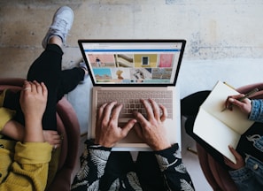 person using microsoft surface laptop on lap with two other people