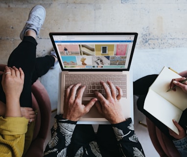 person using microsoft surface laptop on lap with two other people