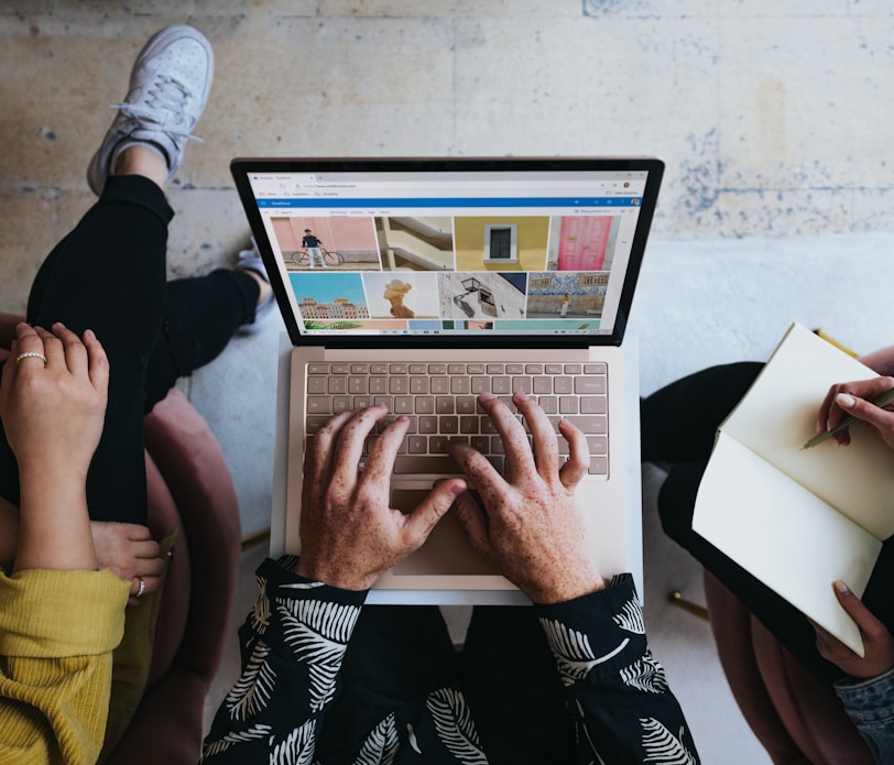 person using microsoft surface laptop on lap with two other people