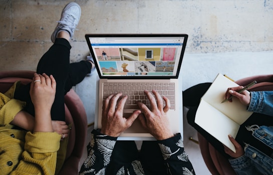 person using microsoft surface laptop on lap with two other people