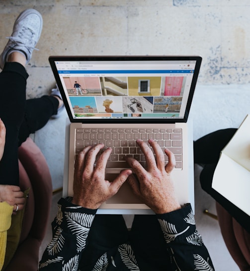 person using microsoft surface laptop on lap with two other people