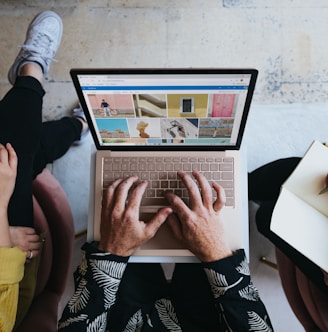 person using microsoft surface laptop on lap with two other people