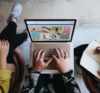 person using microsoft surface laptop on lap with two other people