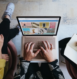 person using microsoft surface laptop on lap with two other people