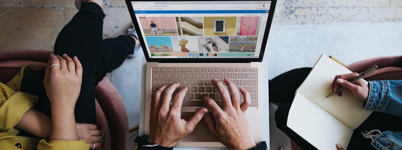 person using microsoft surface laptop on lap with two other people