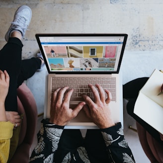 person using microsoft surface laptop on lap with two other people