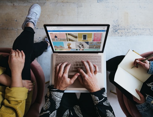 person using microsoft surface laptop on lap with two other people