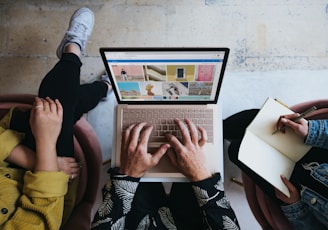 person using microsoft surface laptop on lap with two other people