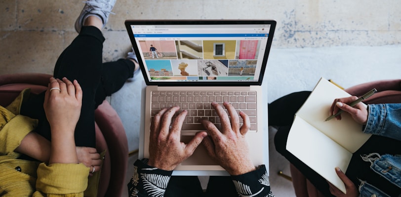 person using microsoft surface laptop on lap with two other people