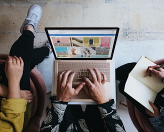 person using microsoft surface laptop on lap with two other people