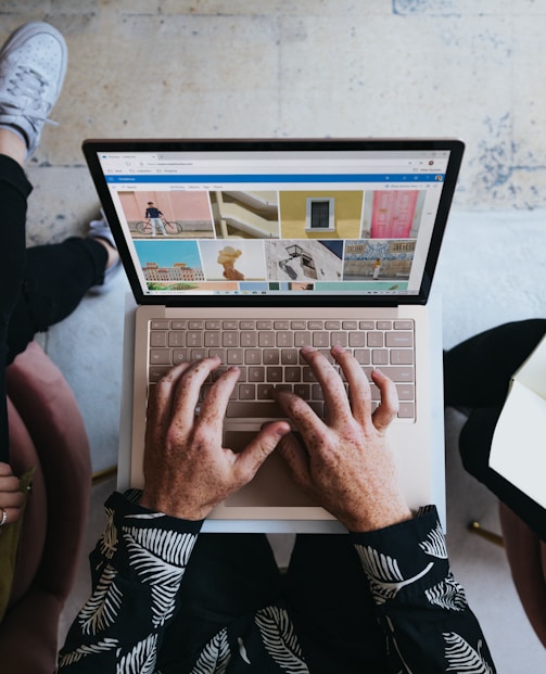 person using microsoft surface laptop on lap with two other people