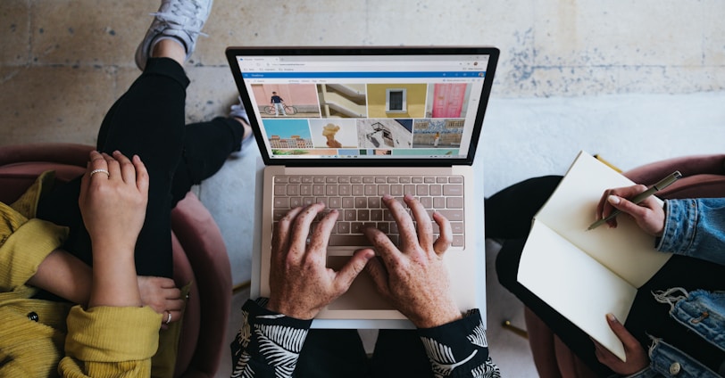 person using microsoft surface laptop on lap with two other people